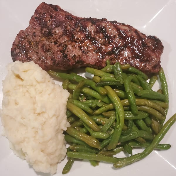 Grilled steak, mashed potatoes, and green beans on a white plate at The Wardhurst Restaurant.